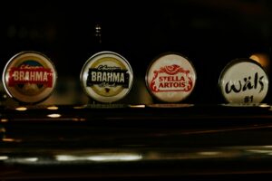 Close-up of various beer taps in dimly lit Brazilian bar, showcasing popular brands.